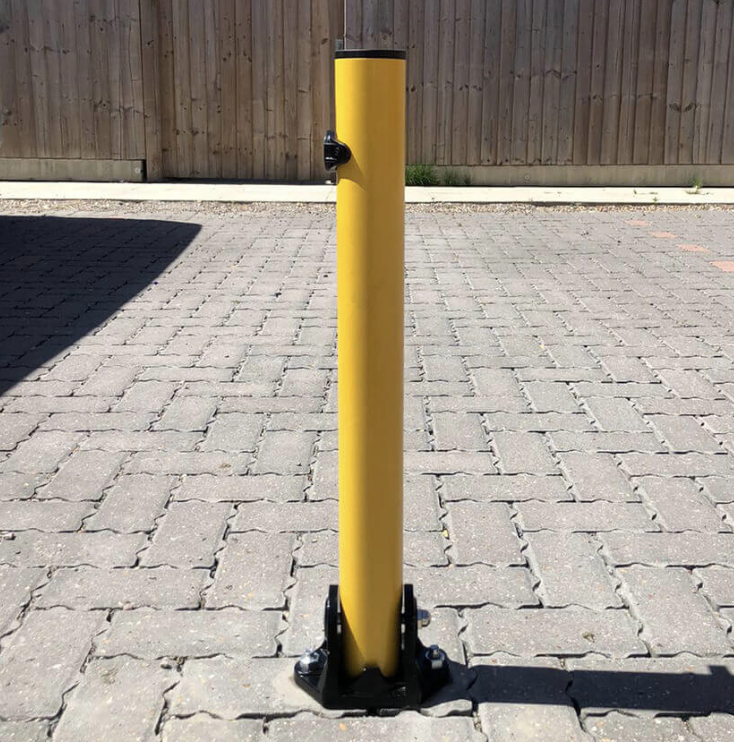 Yellow fold-down parking post installed on a block paving driveway
